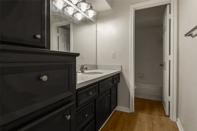 full bath featuring wood finished floors, vanity, and baseboards