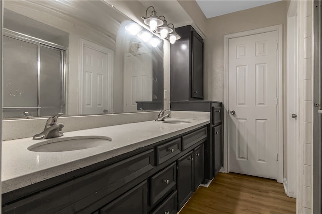 full bathroom with a stall shower, double vanity, a sink, and wood finished floors