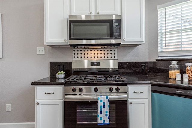 kitchen featuring white cabinetry, a wealth of natural light, stainless steel appliances, and dark stone countertops