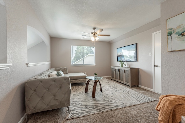 living room with a textured ceiling, carpet flooring, and ceiling fan