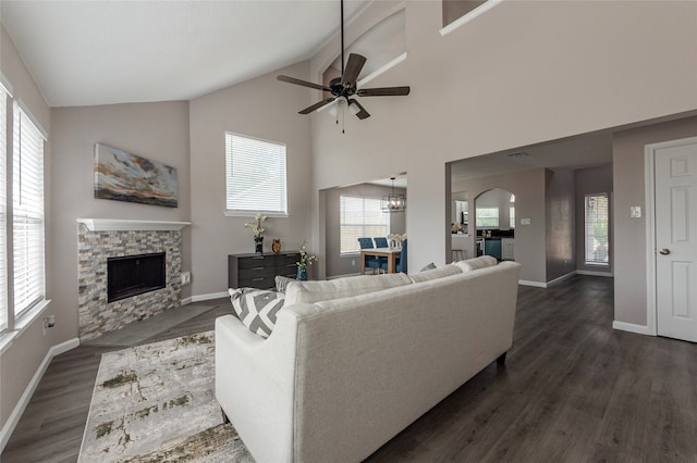 living room featuring ceiling fan with notable chandelier, plenty of natural light, dark hardwood / wood-style flooring, and a fireplace