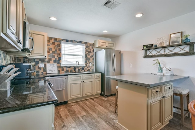 kitchen featuring a breakfast bar area, stainless steel appliances, visible vents, a sink, and a peninsula