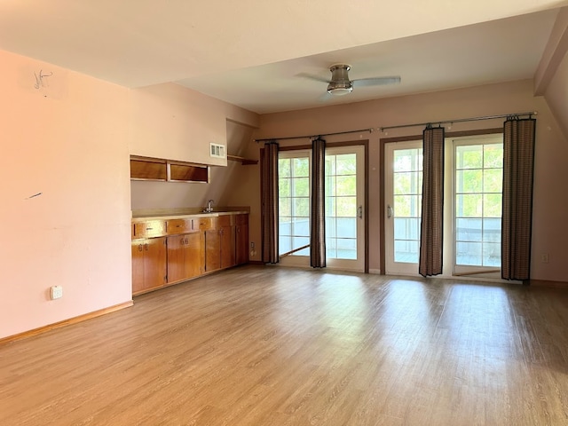 unfurnished living room featuring ceiling fan, light hardwood / wood-style floors, and sink