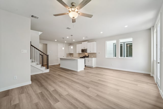 unfurnished living room with plenty of natural light, light hardwood / wood-style floors, and ceiling fan