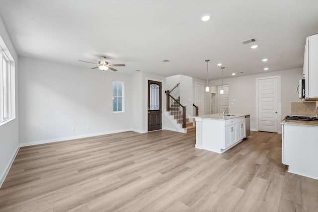 kitchen with pendant lighting, a healthy amount of sunlight, white cabinets, and light hardwood / wood-style flooring