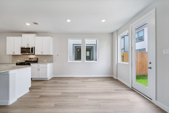 kitchen featuring plenty of natural light, white cabinets, light hardwood / wood-style flooring, and appliances with stainless steel finishes