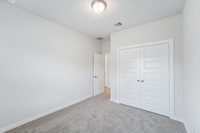 unfurnished bedroom featuring light carpet and a closet