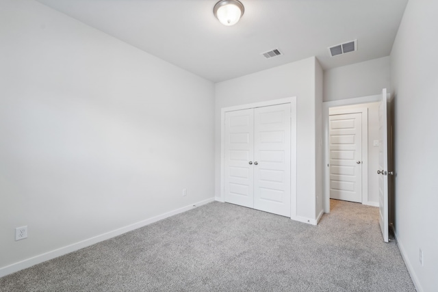 unfurnished bedroom with light carpet and a closet