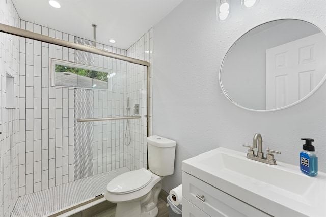 bathroom with a shower with door, vanity, and toilet