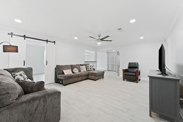 living room with ceiling fan, light hardwood / wood-style floors, a barn door, and crown molding