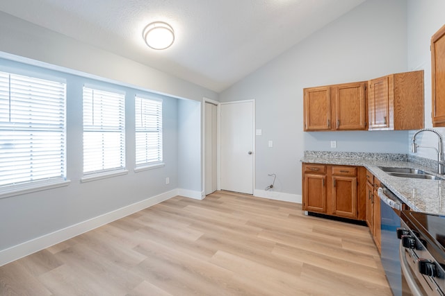 kitchen with stainless steel dishwasher, high vaulted ceiling, light hardwood / wood-style floors, light stone countertops, and sink