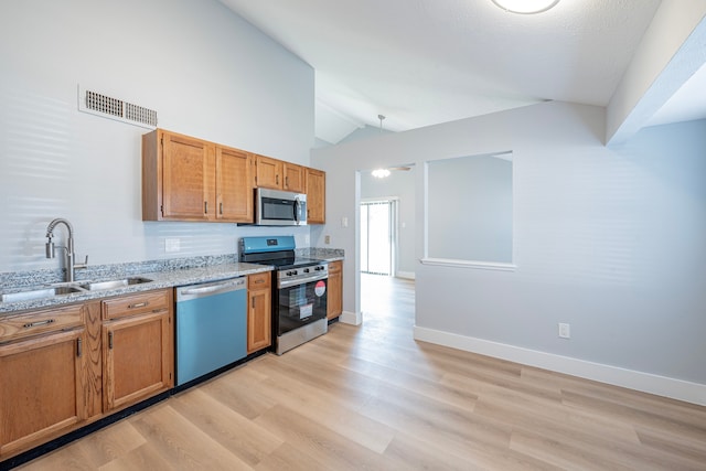 kitchen with sink, stainless steel appliances, light hardwood / wood-style flooring, and light stone counters