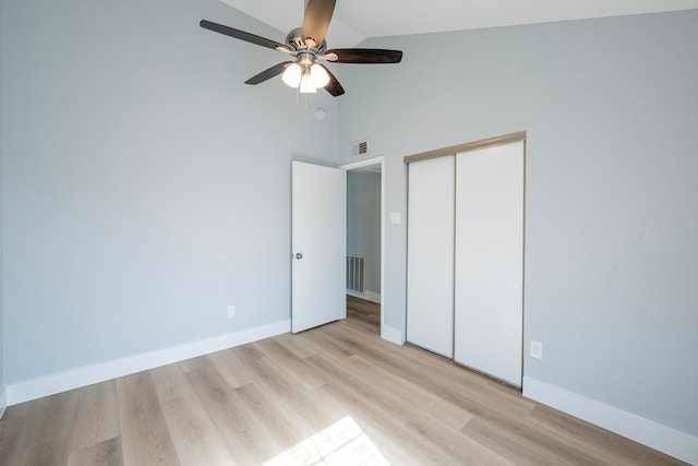 unfurnished bedroom featuring ceiling fan, a closet, high vaulted ceiling, and light wood-type flooring