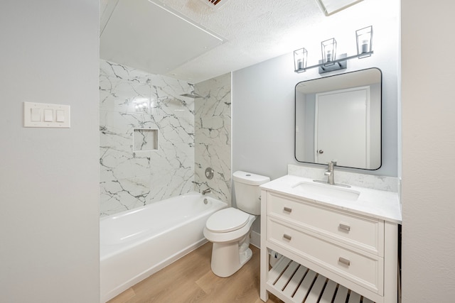 full bathroom with hardwood / wood-style floors, vanity, a textured ceiling, toilet, and tiled shower / bath combo