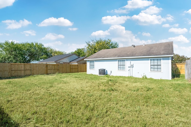 back of property with central AC and a yard