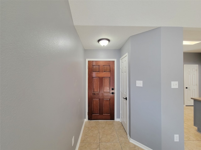 doorway featuring a textured ceiling and light tile patterned floors