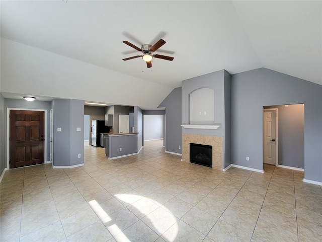 unfurnished living room featuring lofted ceiling, ceiling fan, a tiled fireplace, and light tile patterned floors