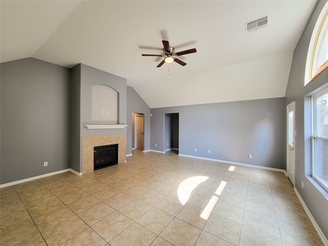 unfurnished living room with ceiling fan, light tile patterned flooring, lofted ceiling, and a tiled fireplace