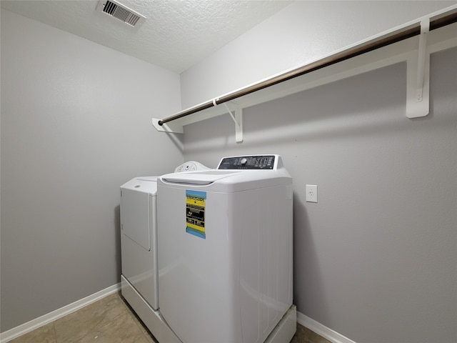 laundry room with a textured ceiling, light tile patterned floors, and washer and dryer