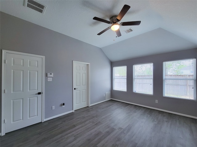 empty room with a textured ceiling, lofted ceiling, dark hardwood / wood-style floors, and ceiling fan