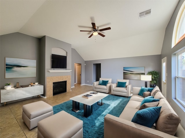 tiled living room featuring vaulted ceiling, a tiled fireplace, and ceiling fan