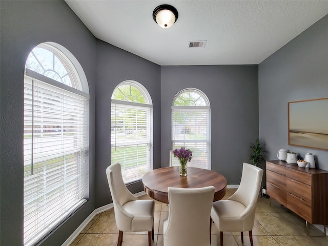 dining room featuring a textured ceiling, light tile patterned flooring, and a healthy amount of sunlight