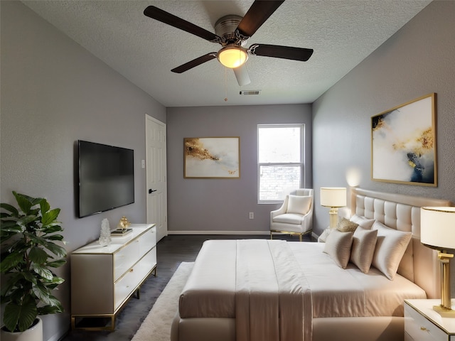 bedroom with ceiling fan, dark hardwood / wood-style floors, and a textured ceiling