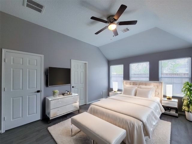 bedroom with vaulted ceiling, ceiling fan, dark wood-type flooring, and a textured ceiling