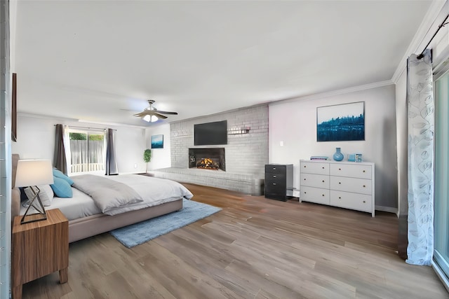 bedroom featuring light hardwood / wood-style floors, a brick fireplace, ceiling fan, and crown molding