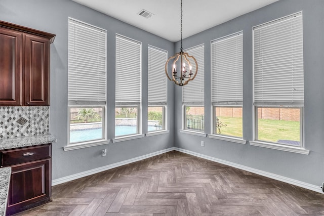 unfurnished dining area featuring dark parquet floors and an inviting chandelier