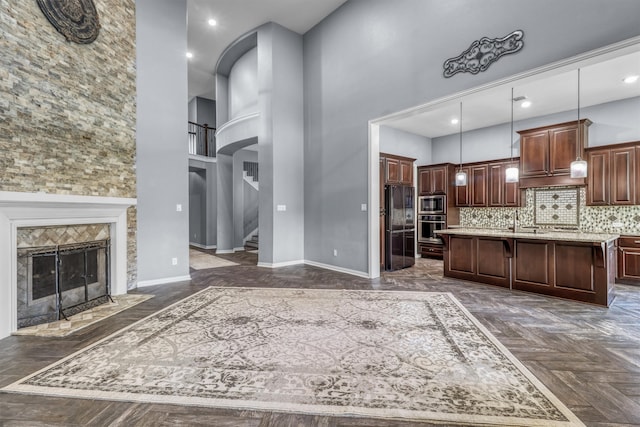 kitchen featuring dark parquet floors, a kitchen island with sink, hanging light fixtures, and a high ceiling