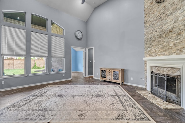 unfurnished living room featuring a fireplace, dark parquet flooring, high vaulted ceiling, and ceiling fan