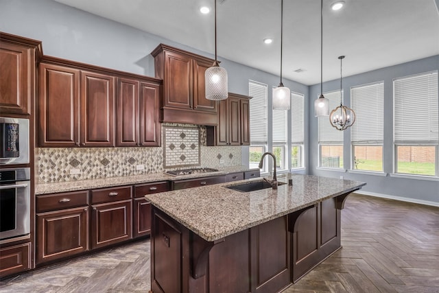 kitchen with a breakfast bar, backsplash, a center island with sink, sink, and appliances with stainless steel finishes