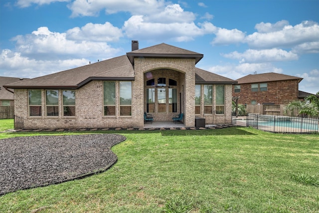 rear view of house with a yard, a patio, a fenced in pool, and cooling unit