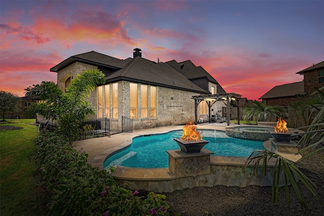 pool at dusk featuring a patio area, an in ground hot tub, and a fire pit