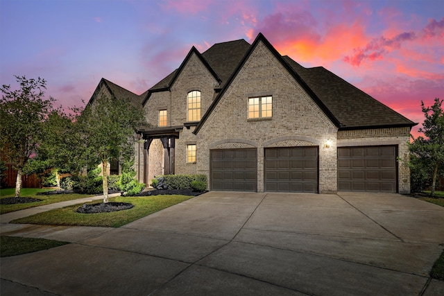 french country home featuring a lawn and a garage