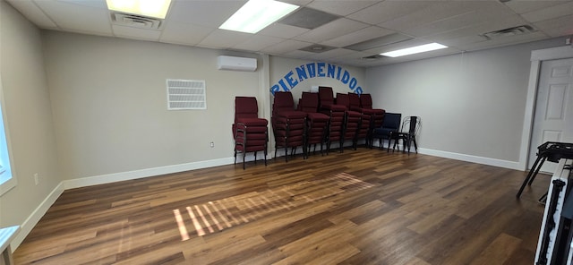 interior space with a paneled ceiling, dark hardwood / wood-style flooring, and a wall mounted AC