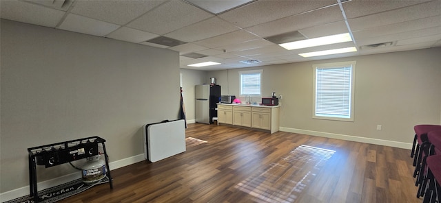 living room featuring sink, wood-type flooring, and a drop ceiling