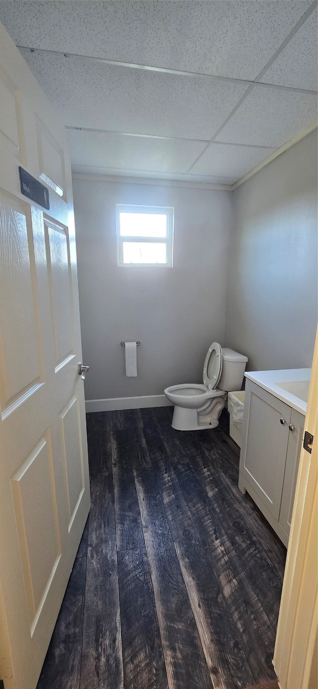 bathroom featuring hardwood / wood-style flooring, vanity, a paneled ceiling, and toilet