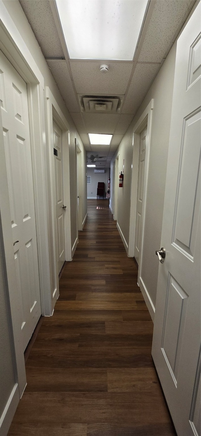 hallway featuring dark hardwood / wood-style floors and a paneled ceiling