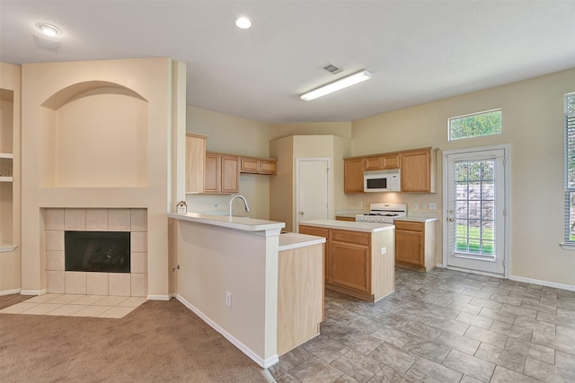 kitchen with white appliances, sink, light brown cabinets, a fireplace, and a center island