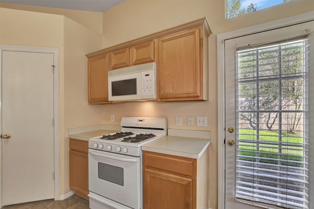 kitchen featuring light brown cabinets, light tile patterned flooring, and white appliances