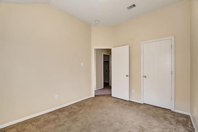 unfurnished bedroom with light colored carpet and vaulted ceiling