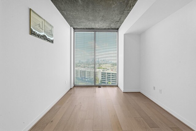 empty room with expansive windows and wood-type flooring