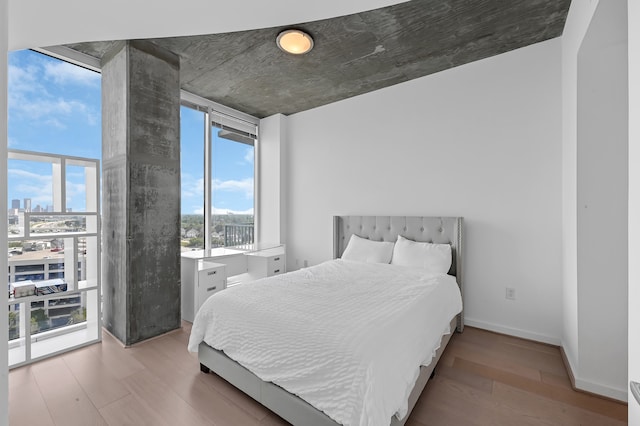 bedroom featuring a wall of windows, light hardwood / wood-style flooring, and multiple windows