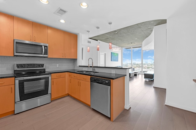 kitchen featuring light wood-type flooring, tasteful backsplash, appliances with stainless steel finishes, sink, and kitchen peninsula