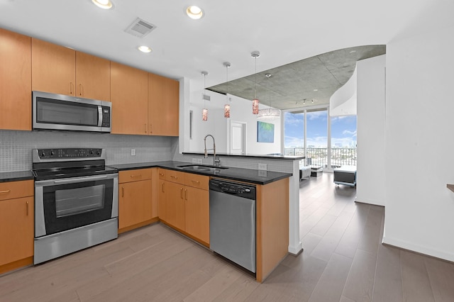 kitchen featuring tasteful backsplash, visible vents, appliances with stainless steel finishes, a sink, and a peninsula