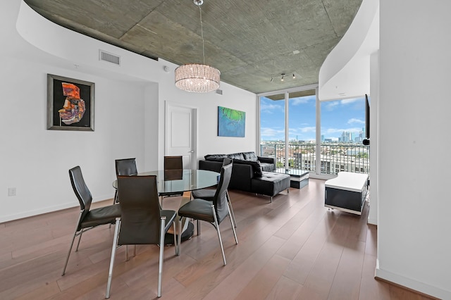 dining area featuring wood-type flooring, a notable chandelier, and floor to ceiling windows