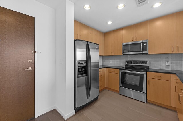 kitchen featuring appliances with stainless steel finishes, light hardwood / wood-style flooring, light brown cabinetry, and tasteful backsplash