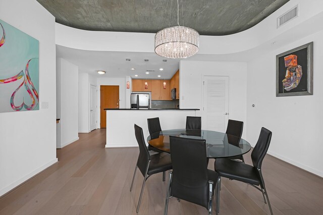 dining room featuring wood-type flooring and an inviting chandelier